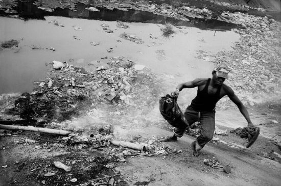尼日利亚拉各斯市，奥拉迪波(Oladipo)电脑市场。电脑市场中废弃的零件都被倾倒进运河中，在运河水位 低的时候，拾荒者将垃圾从河中拖拽出来。由于这些都是有毒废弃物，使得运河边有许多燃烧着的火苗，回收充满危险。